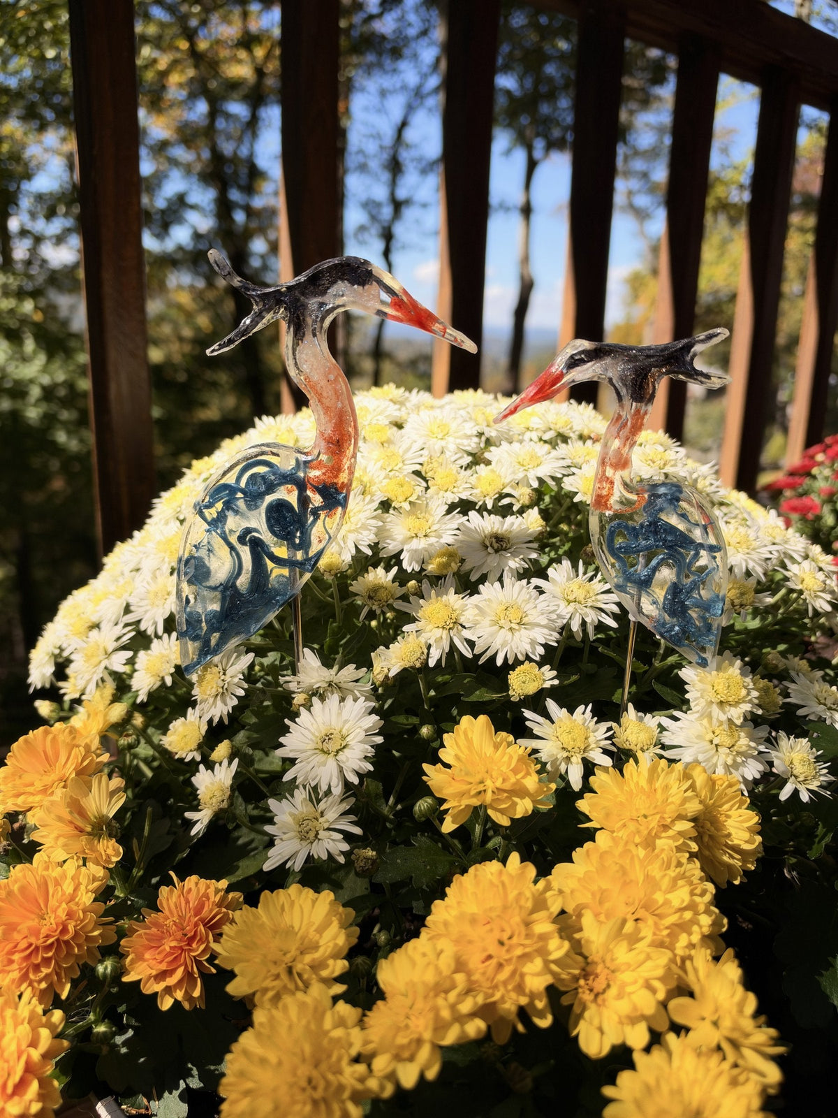 Resin blue herons on sticks in white and yellow mums