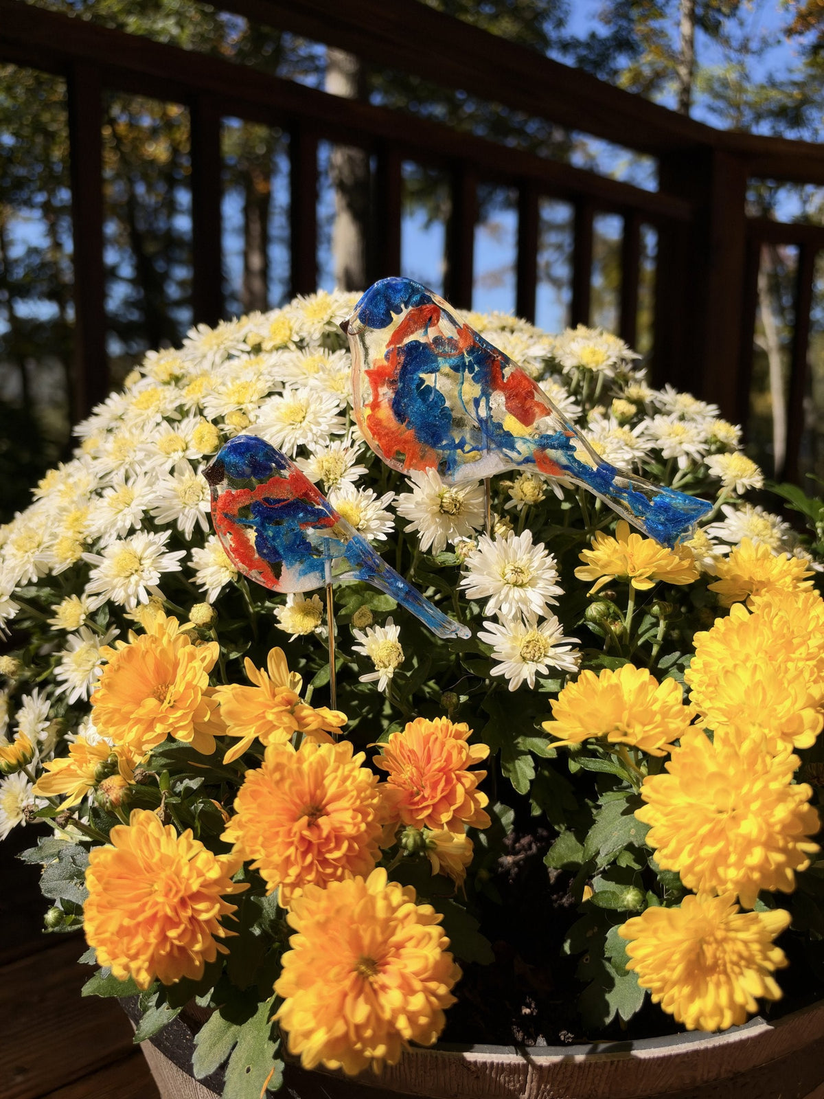 Two resin bluebirds on sticks in white and yellow mums