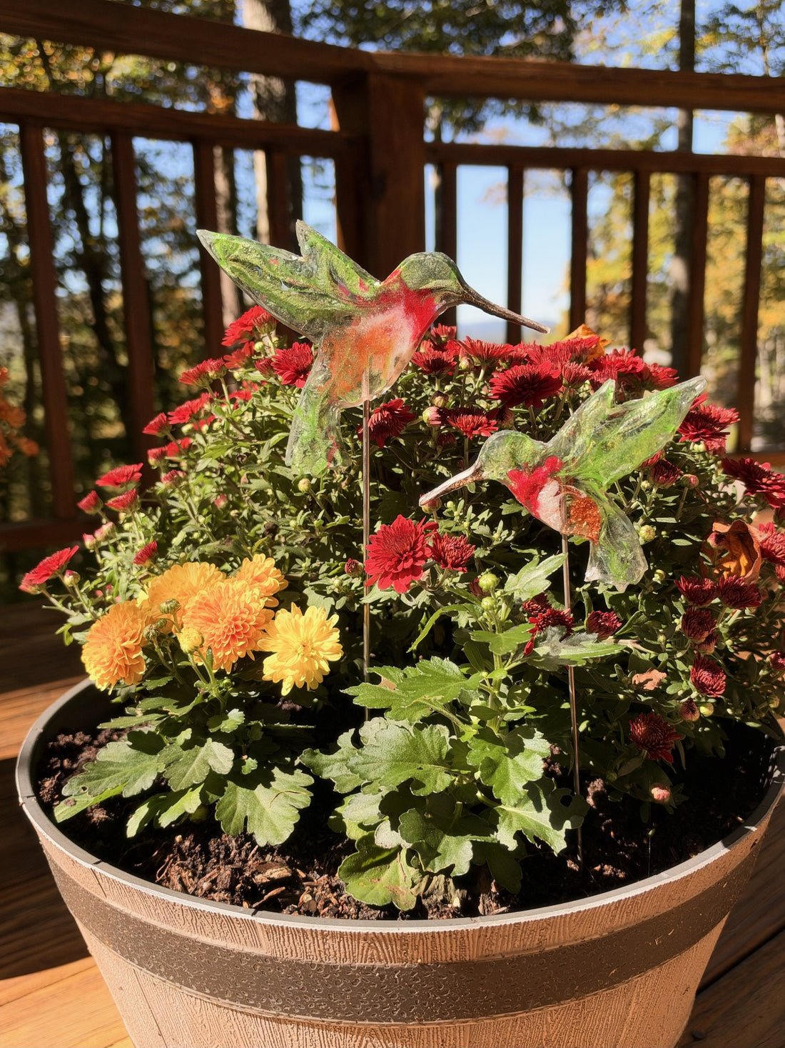 Two resin hummingbirds on sticks in red mums
